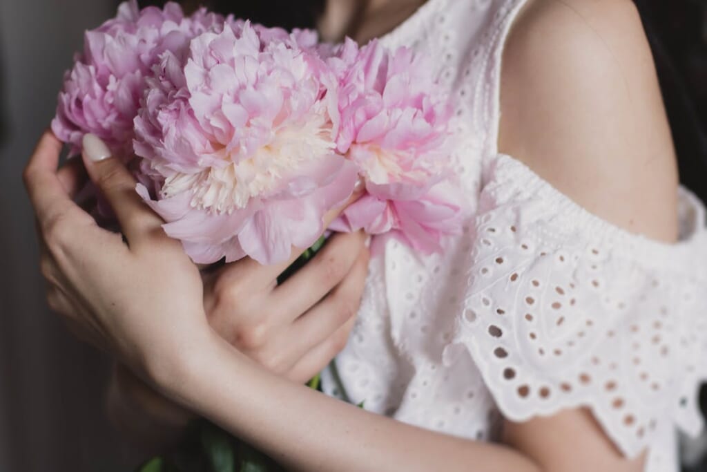 ピンクの花を抱えている女性の手元